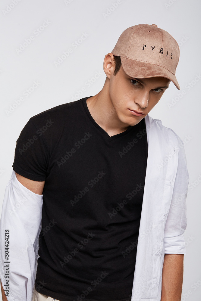 Φωτογραφία Cropped front view shot of a dark-haired man, wearing beige baseball cap with lettering Paris, black t-shirt and white shirt