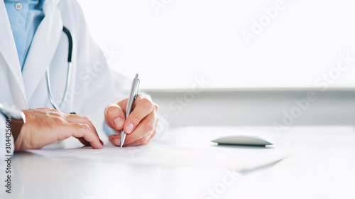 Close up of doctor signing prescription for patient photo
