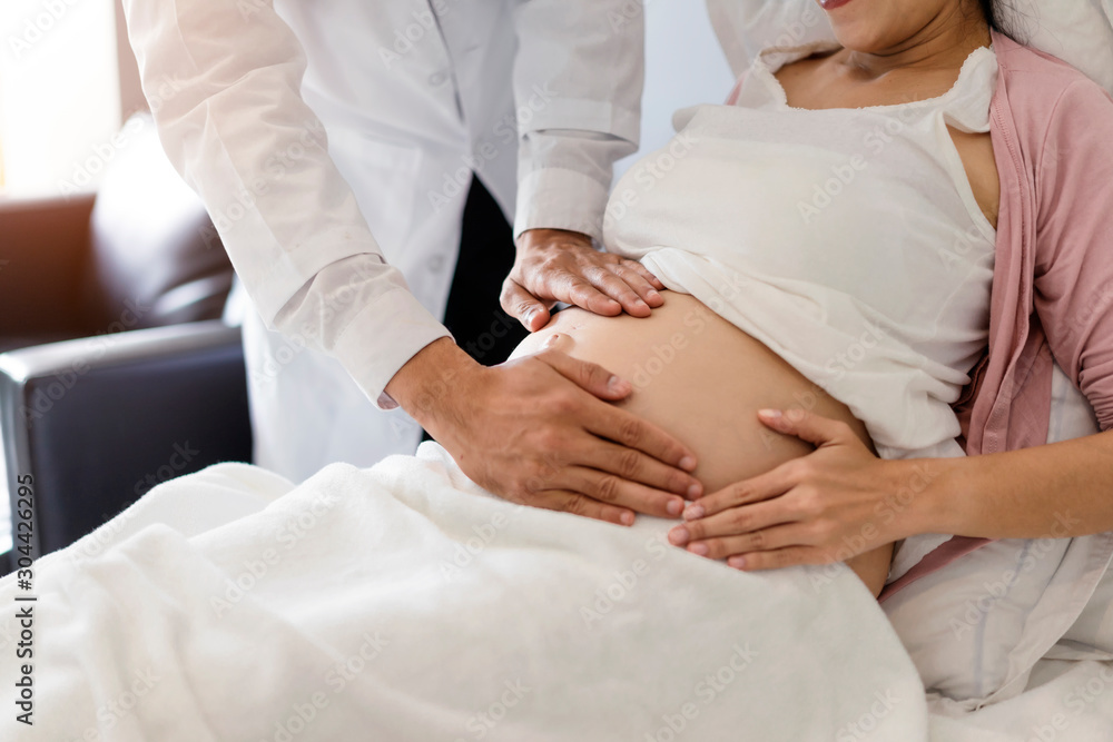 Pregnant women go to the doctor to detect pregnancy as scheduled.The doctor touches the abdomen to check the integrity of the unborn child.