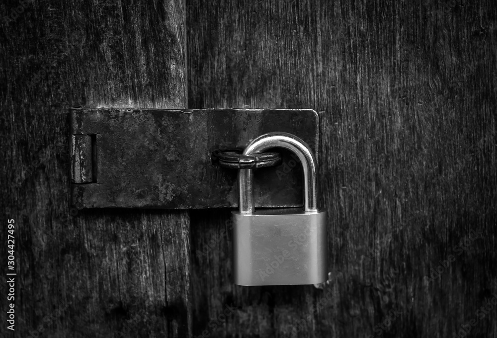 Fototapeta premium Locked padlock with chain at gray wooden door. black and white.
