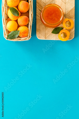 Healthy breakfast. Apricot jam in jar near fresh fruits on blue background top view frame copy space