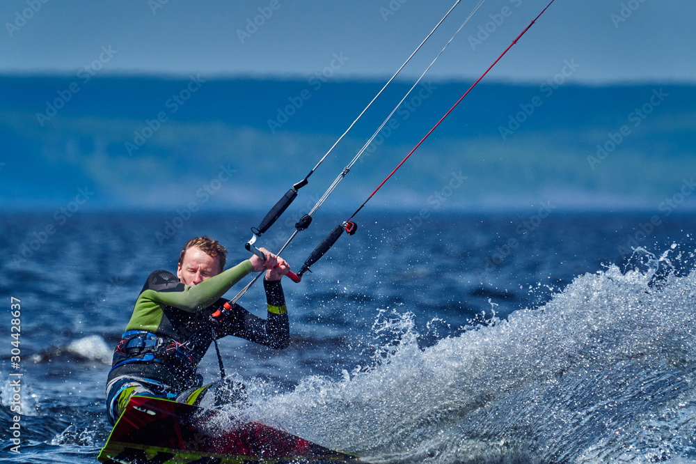 Naklejka premium A male kiter slides on the surface of the water. Splashes of water fly apart. Close-up.