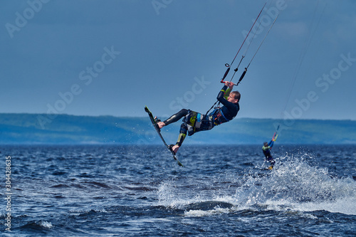 A male kiter slides on the surface of the water. Splashes of water fly apart.