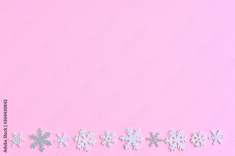 Pink Christmas background with white and silver snowflakes border and empty space for text, selective focus. New year flat lay with snowflakes decorative border. Winter postcard. Pink Christmas background with white and silver snowflakes border and empty space for text, selective focus. New year flat lay with snowflakes decorative border. Winter postcard.