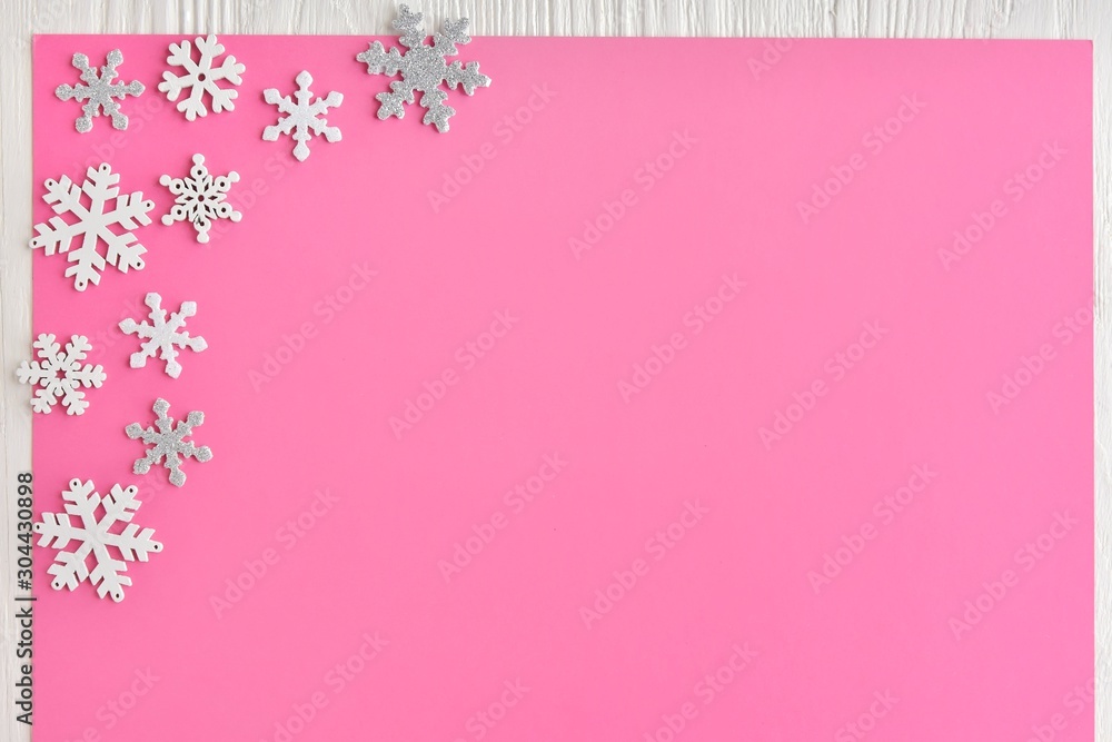 Pink Christmas background with white and silver snowflakes border and empty space for text, selective focus. New year flat lay with snowflakes decorative border. Winter postcard. Pink Christmas background with white and silver snowflakes border and empty space for text, selective focus. New year flat lay with snowflakes decorative border. Winter postcard.