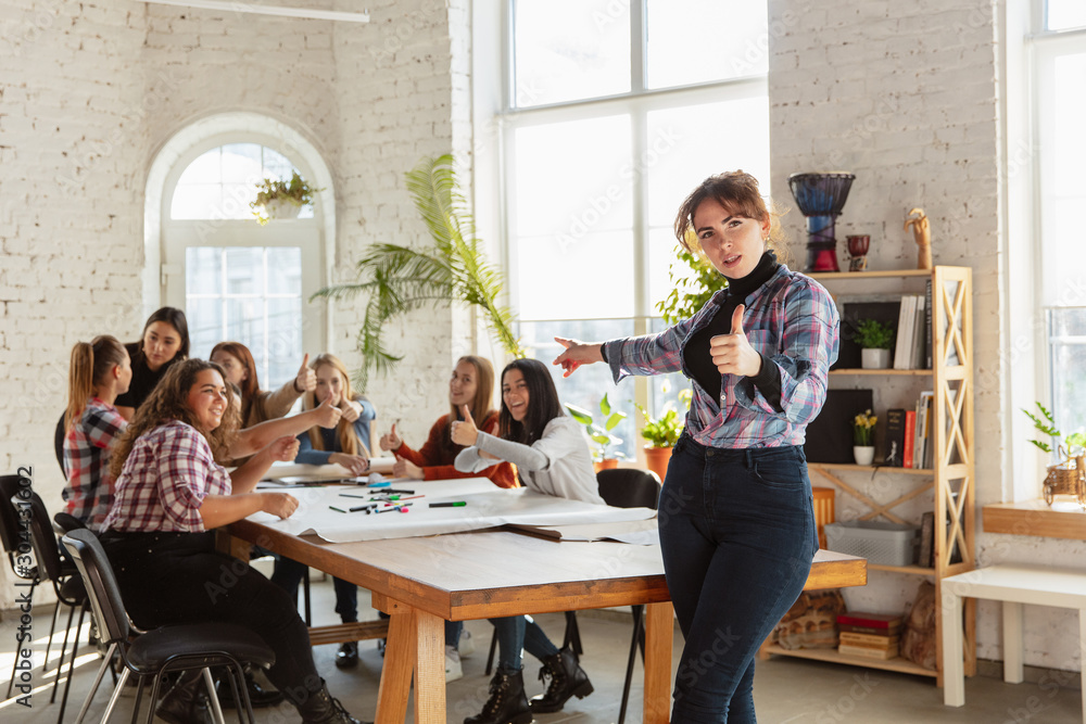 Women's rights and equality at the office. Caucasian businesswomen or young confident model with thumb up in front of coworkers having meeting about problem in workplace, male pressure and harassment.