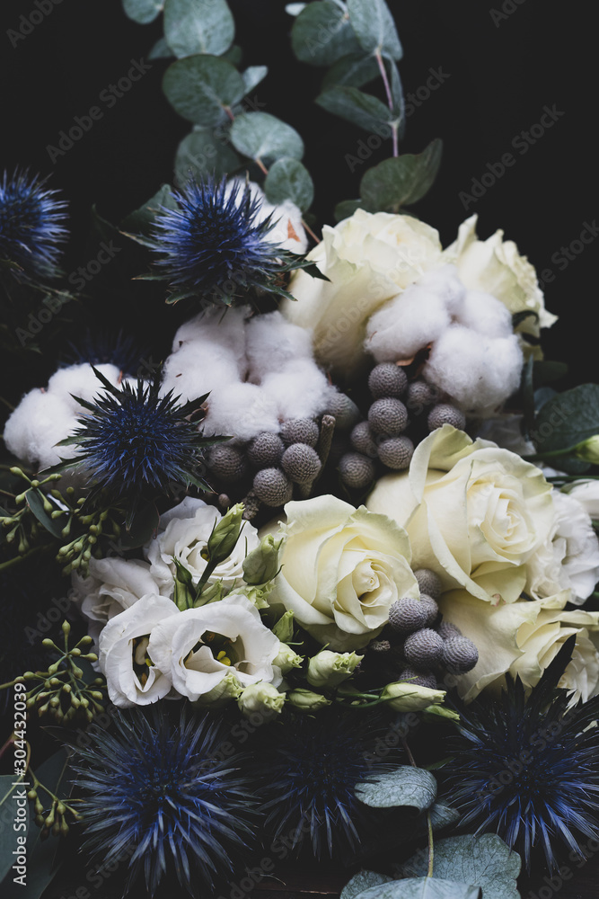 Winter wedding bouquet of white roses, cotton and eringium on a black background. The bride's bouquet.