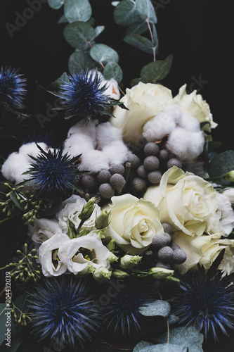 Winter wedding bouquet of white roses, cotton and eringium on a black background. The bride's bouquet.