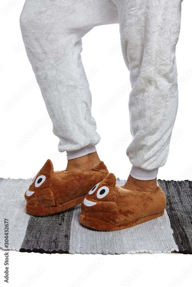 Close-up shot of male legs in white velour trousers and brown plush house  slippers made