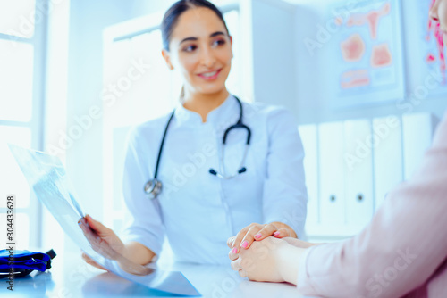 Arab woman doctor and patient discussing something while sitting at the table. Doctor and patient. Medicine and health care concept.