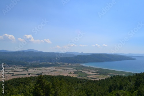 The sea captured from the seaside, there are hills and blue sky. Captured in daytime.