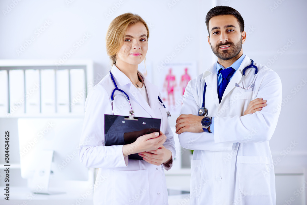 Two doctors all standing together in a consultancy room and holding tablet Two doctors all standing together in a consultancy room and holding tablet