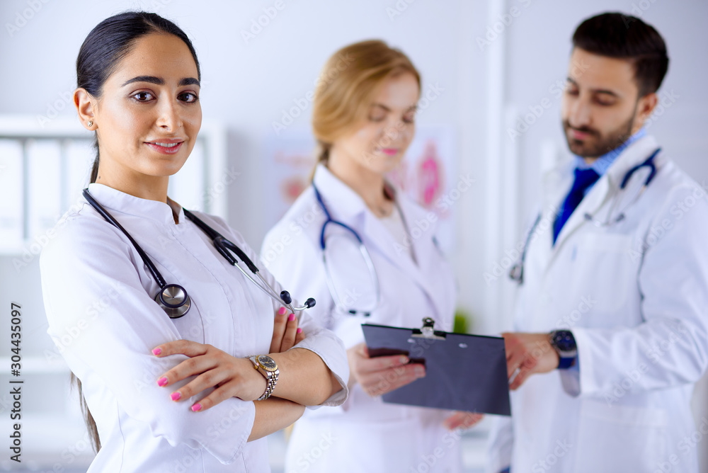 Attractive female arab doctor smiling in front of medical stuff in hospital Attractive female arab doctor smiling in front of medical stuff in hospital