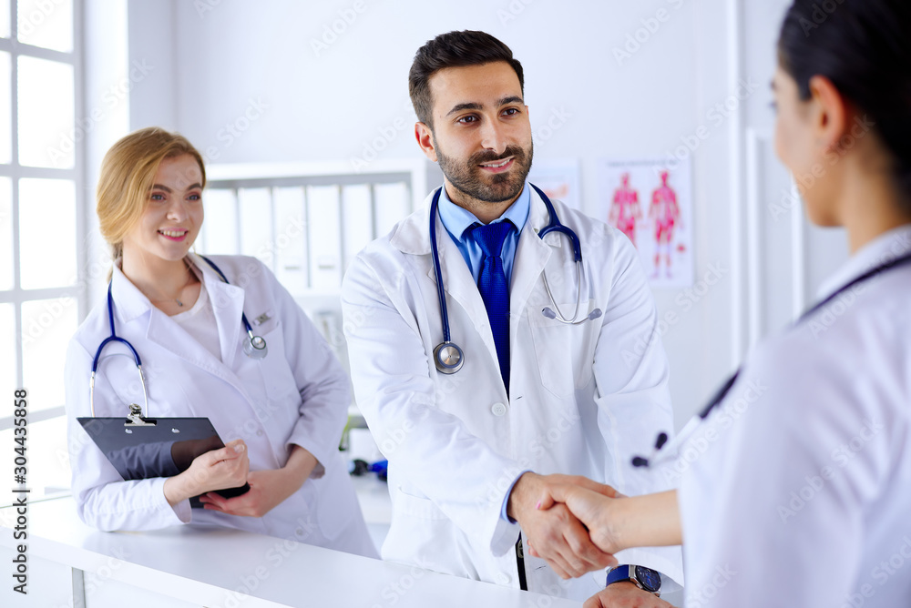 Young arab doctor shakes hands with a nurse in a hospital. Against the background of the human body Young arab doctor shakes hands with a nurse in a hospital. Against the background of the human body