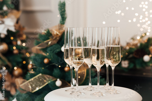 Christmas and New Year celebration with champagne. New Year holiday decorated. Six champagne glasses on the background of Christmas tree lights