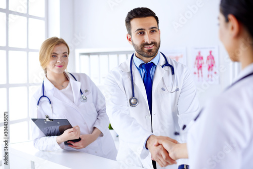 Young arab doctor shakes hands with a nurse in a hospital. Against the background of the human body