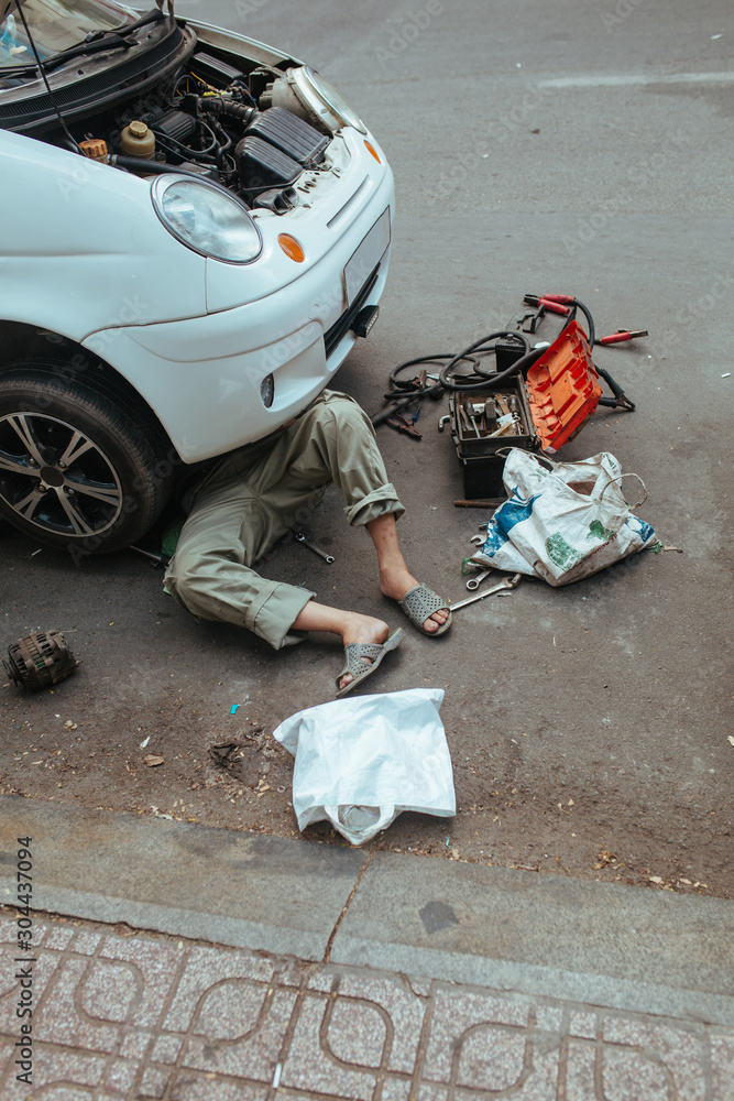 Car repair on the street, man uder the car
