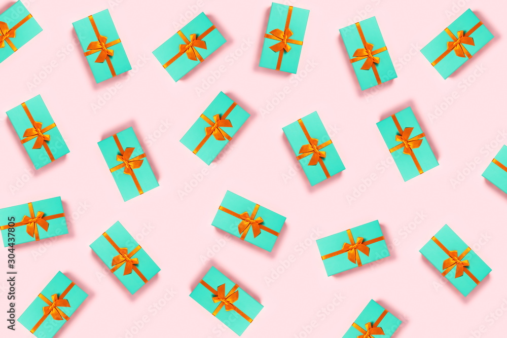 Pattern with orange bow on a mint boxes located on pink background. Pattern with orange bow on a mint boxes located on pink background.