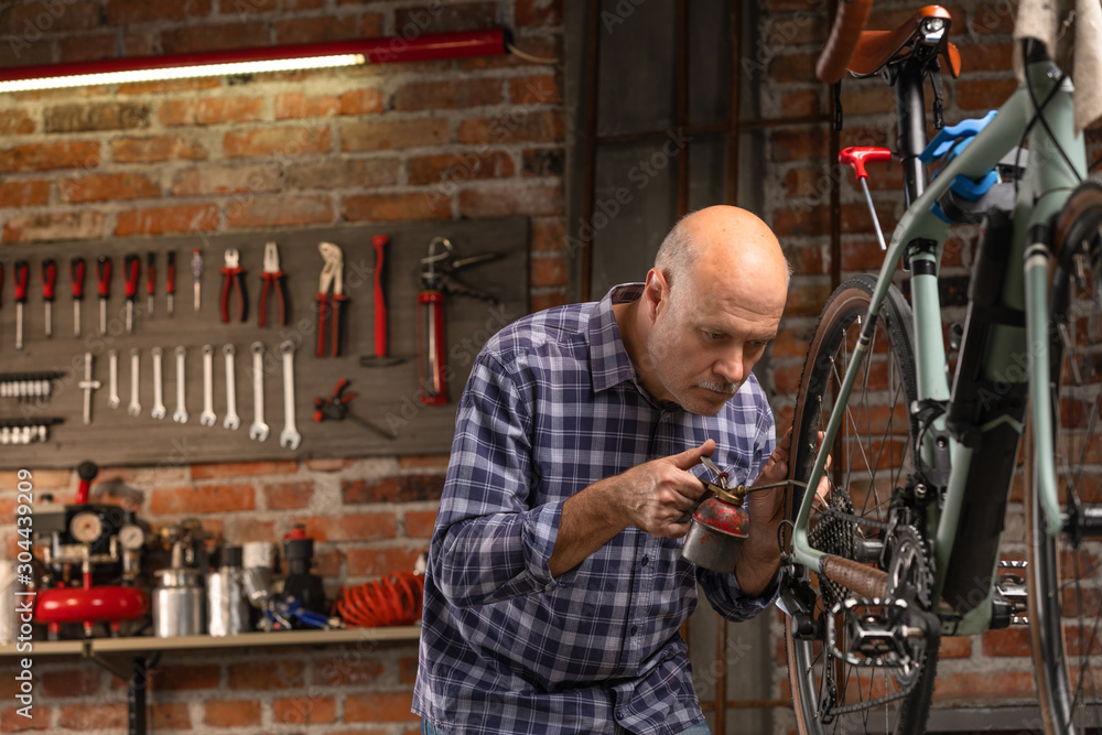 Man oiling the chain on a bicycle in a workshop Man oiling the chain on a bicycle in a workshop
