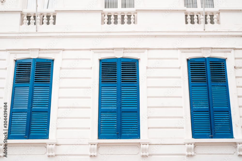 Fototapeta premium Blue shutters on an old white building. Minimalism.