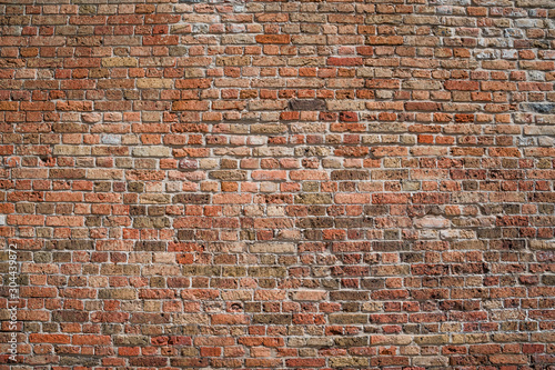 Texture of a medieval brick wall of burgundy, red and brown bricks. General view.
