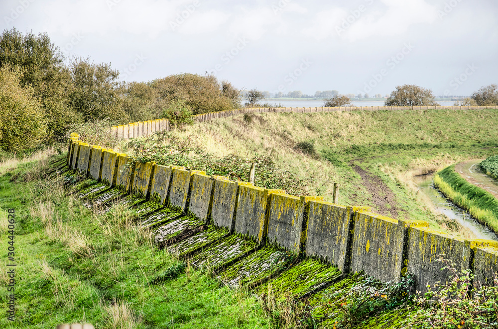 Grassy dike on the north coast of the island of Schouwen-Duiveland, The Netherlands with the weathered concrete of the former sea defense