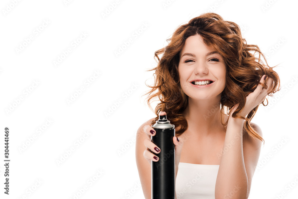 Fototapeta premium happy curly woman holding hair spray bottle isolated on white