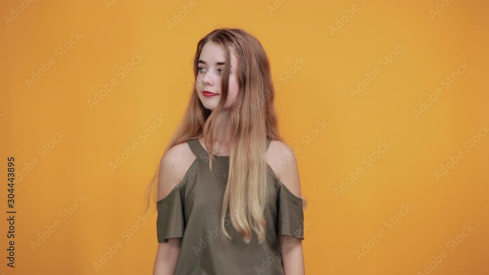Attractive young woman in casual shirt showing on workspace, staying aside isolated on orange wall background studio portrait. People sincere emotions lifestyle concept. Attractive young woman in casual shirt showing on workspace, staying aside isolated on orange wall background studio portrait. People sincere emotions lifestyle concept.