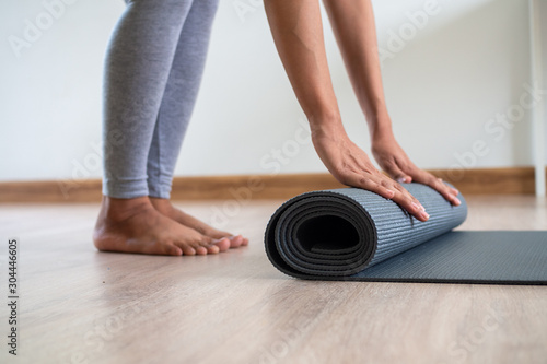 Slim Asian women collecting yoga mats after exercising