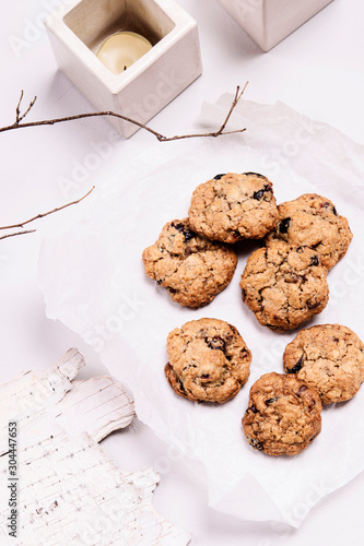 Christmas cranberry and chocolate oatmeal cookies on white background decorated birch bark, branches and candles. Selective focus