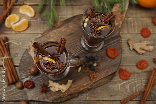 mulled wine hot drink or tea with spices and spices on a wooden background with a branch of spruce. Traditional winter drink. Christmas concept, background, banner, menu. Top view. Flat lay.