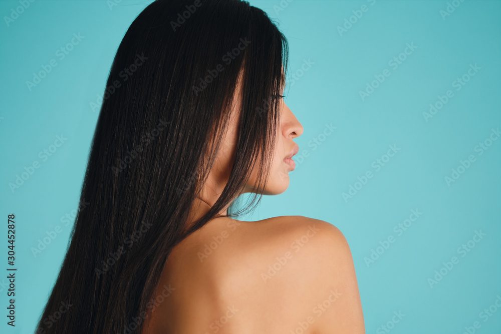 Side view of beautiful Asian girl with dark long hair sensually posing over colorful background isolated