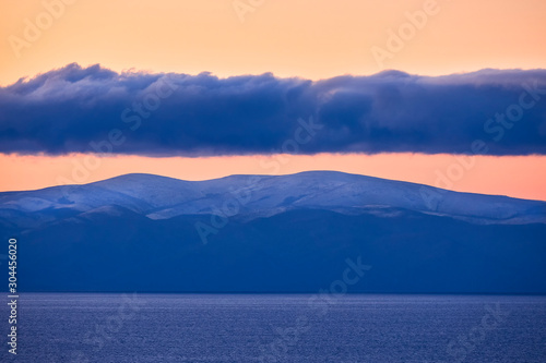 Clouds over mountains and lake at sunrise