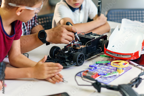 Wallpaper Mural Male electronic engineer with european school children working in smart school lab and testing model of radio controlled electric car. Torontodigital.ca