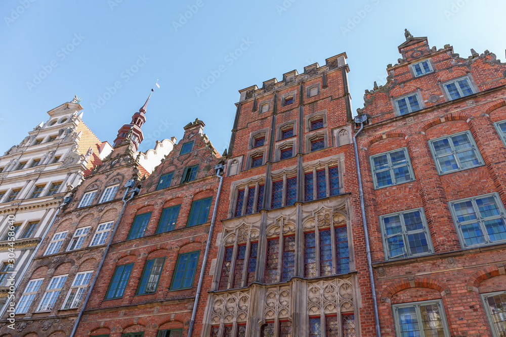 Obraz premium Building facades of red brick houses on sky background, bottom view on a sunny day