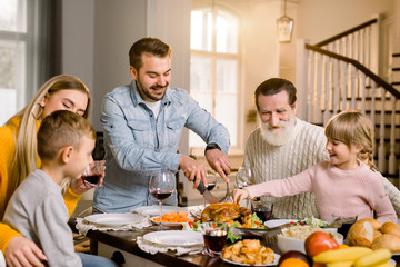 happy excited family celebrating thanksgiving while cutting turkey
