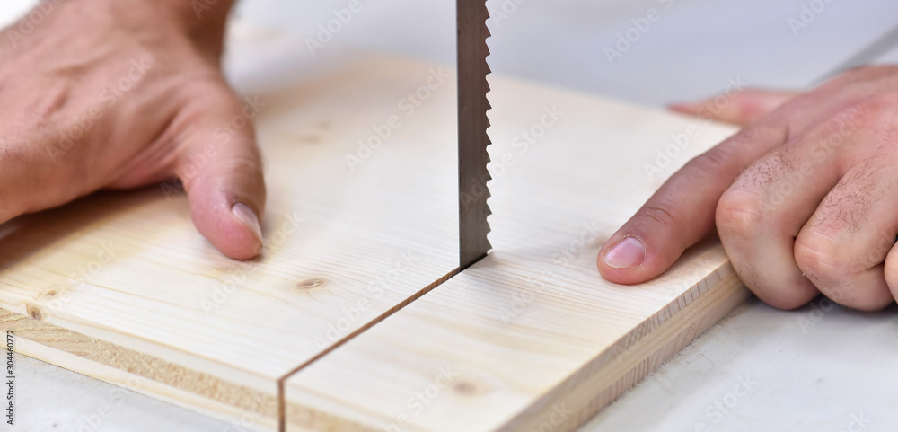 joiner in the workshop saws a wooden board with a sawing machine - detail joiner in the workshop saws a wooden board with a sawing machine - detail