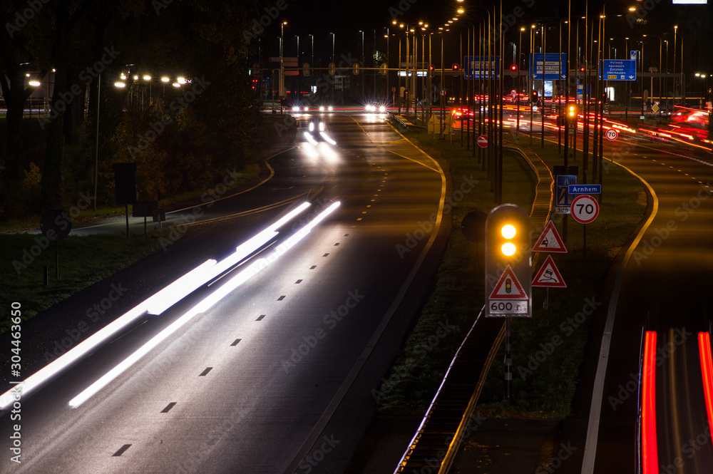 Intersection at night with traffic lights and traffic blurred by motion in Arnhem, Netherlands