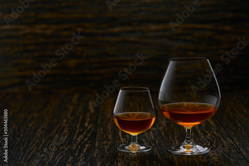 Two glasses of brandy or cognac on a wooden table with copy space.