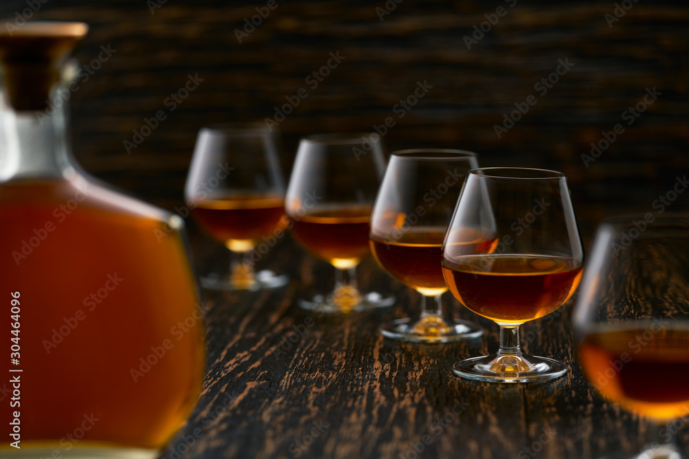 glasses of cognac on a wooden table with the silhouette of a bottle of cognac. glasses of cognac on a wooden table with the silhouette of a bottle of cognac.