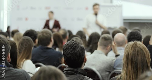 Wallpaper Mural Business forum with man speaker starting to talk in large audience of people on blur background. Viewers clapping and photographing smartphone. Public speech and education concept, view from viewers. Torontodigital.ca