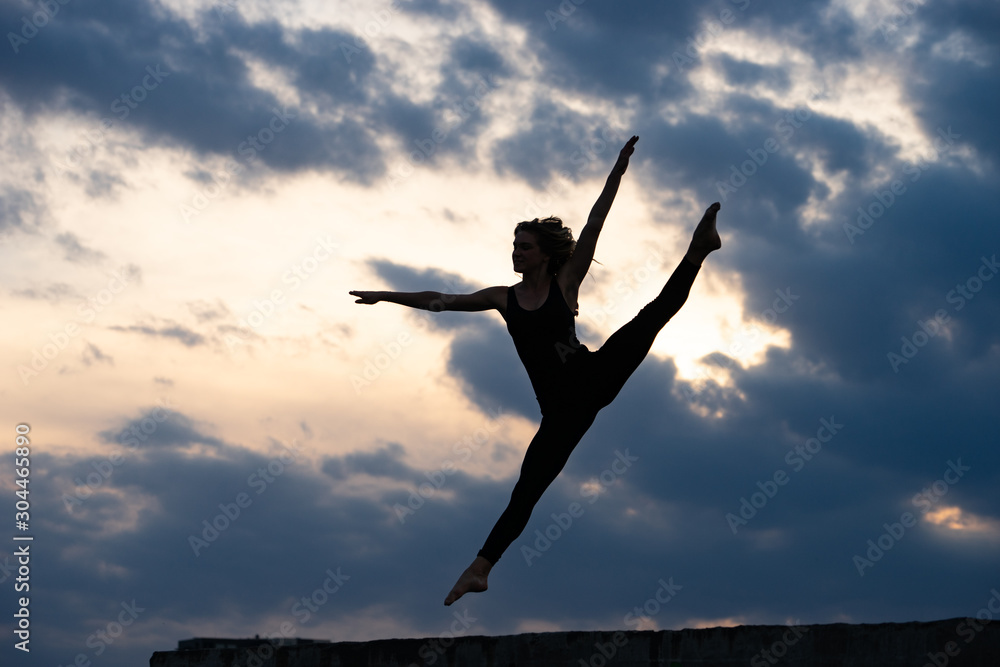 Young woman dancer jumping on outdoor sunrise background. Concept of freedom and happy lifestyle