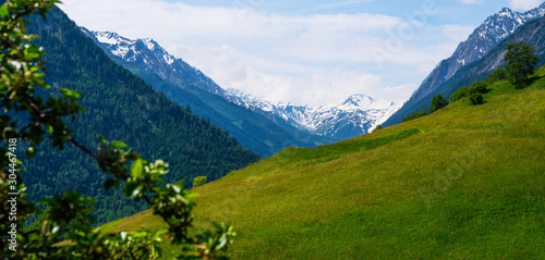 Beautiful view of idyllic Swiss alpine mountains scenery with meadows and snow capped mountain peaks on a beautiful sunny day with blue sky in springtime. Beauty world.