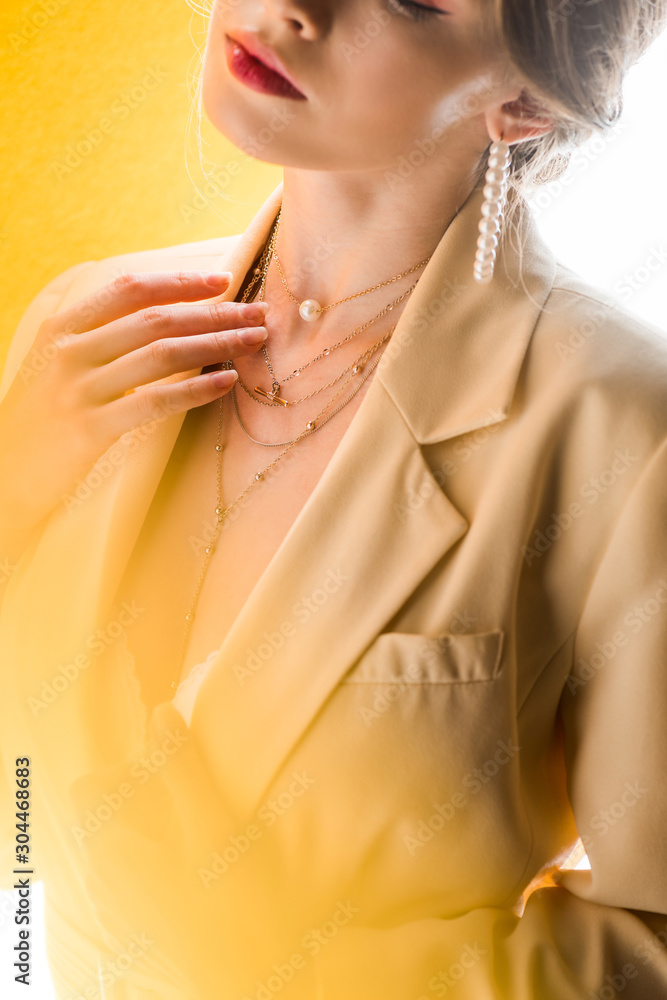 cropped view of woman touching necklace on white and yellow