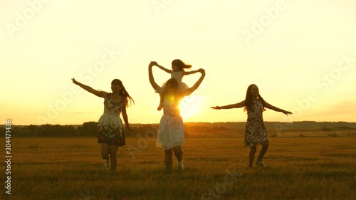 happy childhood concept. Happy young family with a child run across field in flight at sunset light. Mother and daughters walks in park and play in the meadow in sun. concept of life of large family