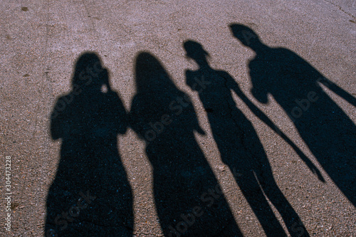 Shadows of four people on the pavement