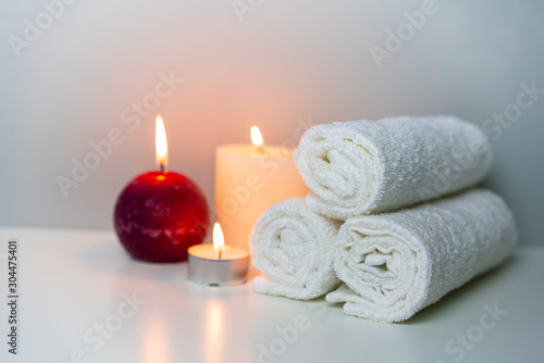 SPA and wellness photo with stack of white towels and candles light, horizontal orientation.