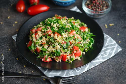 Traditional oriental salad Tabbouleh with bulgur and parsley on a dark background.