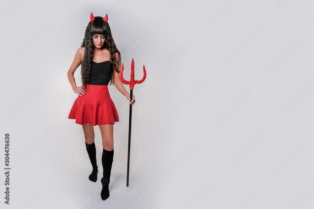 An isolated demon looks down with a trident in his hands. Demon girl with a trident in her hands and horns.