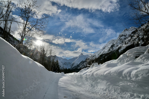 Eine Stra  e in einer Alpinen Winterlandschaft